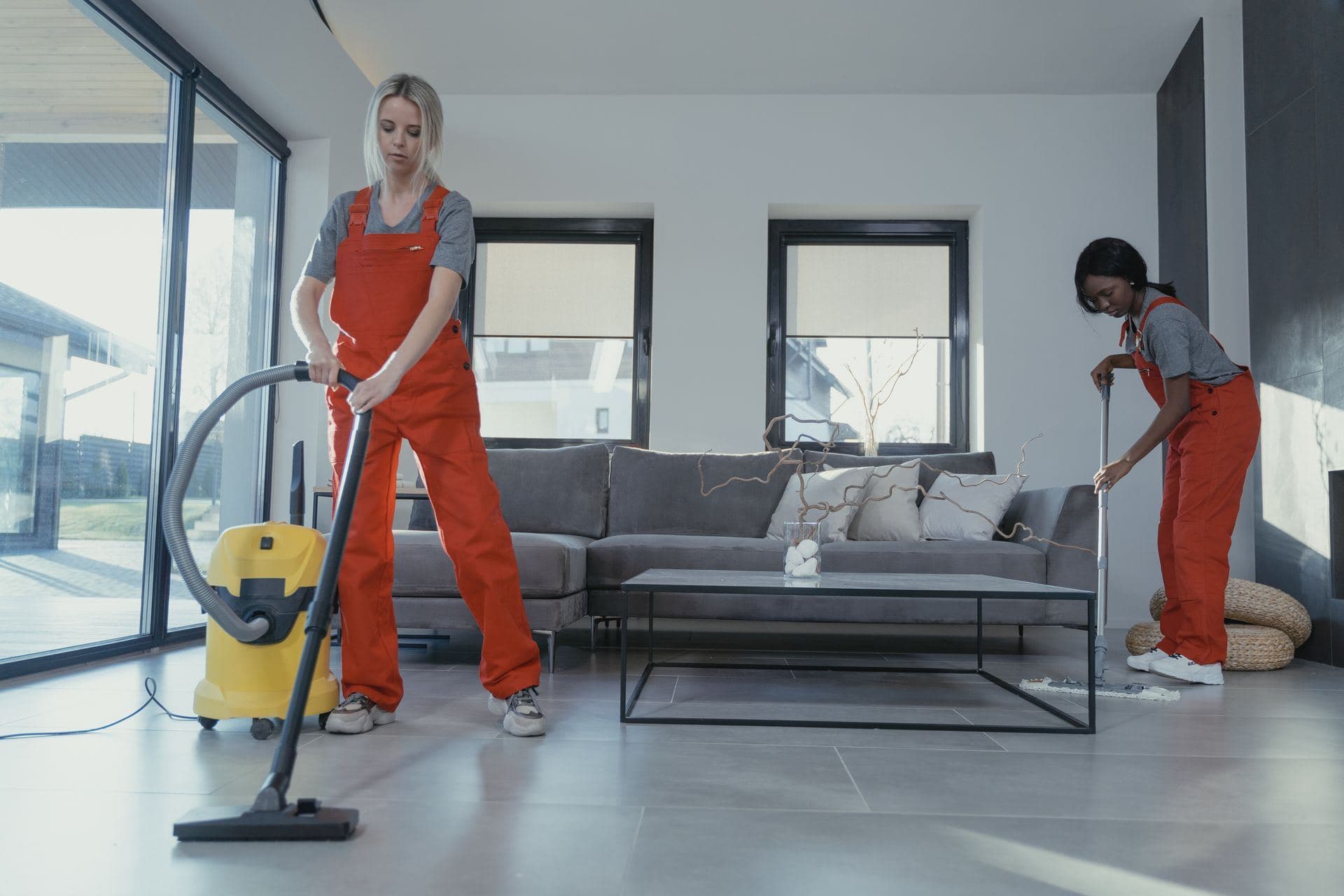 Two cleaners vacuuming and mopping a modern living room