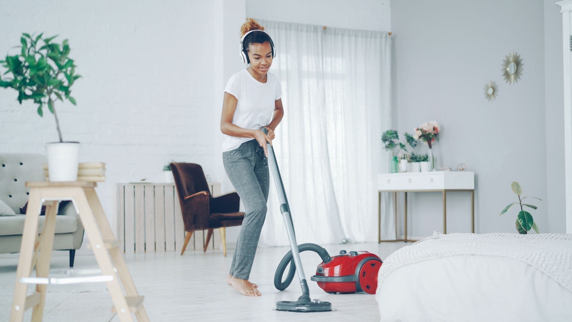 Cleaner vacuuming a white living room floor