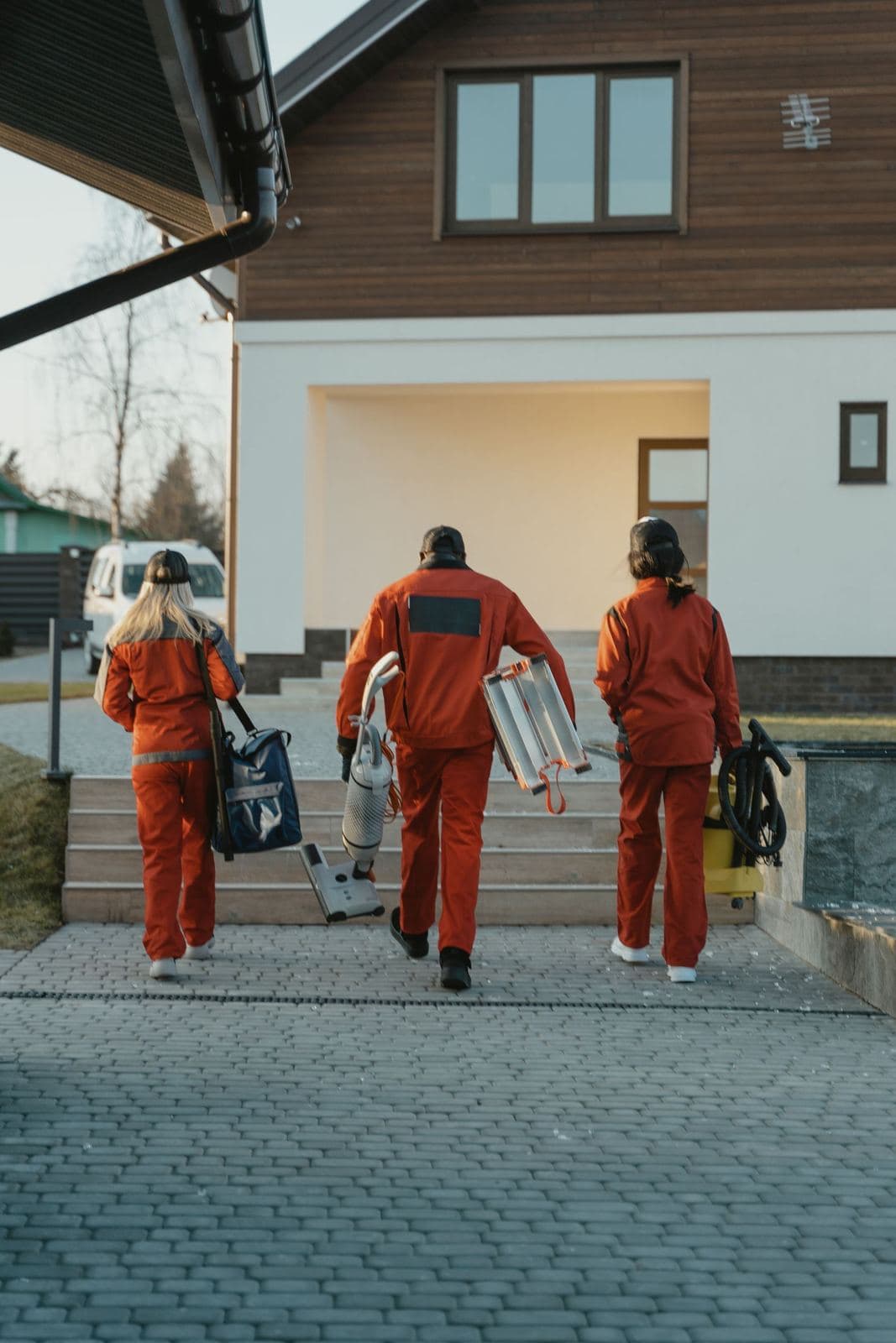 Cleaning crew carrying equipment up to a house